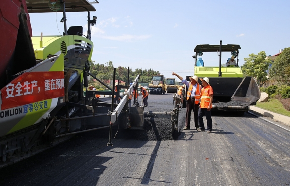 攤鋪機(jī)、壓路機(jī)等設(shè)備緊張有序運(yùn)行，高達(dá)170℃的瀝青混合料炙烤著公路人